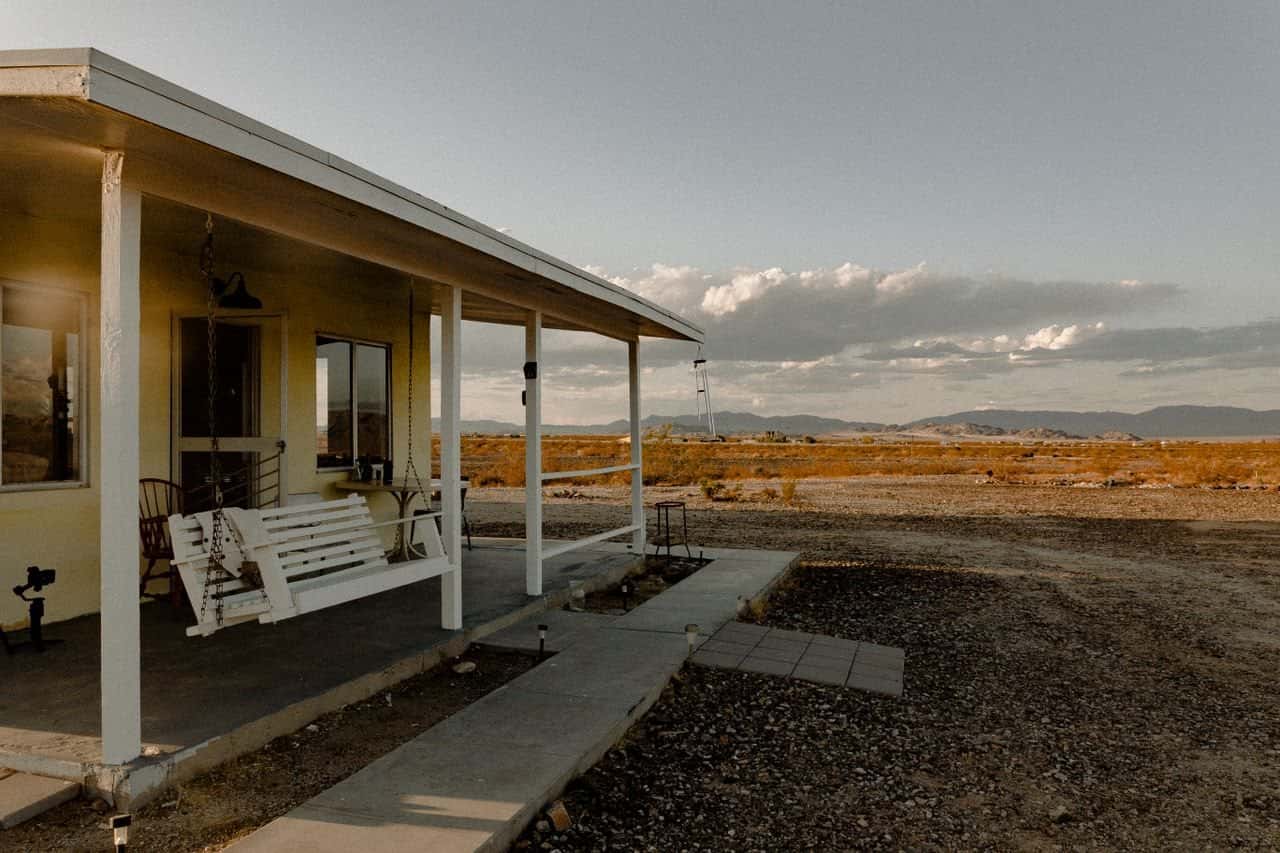 A front porch with a swing, looking out over open desert in early light.