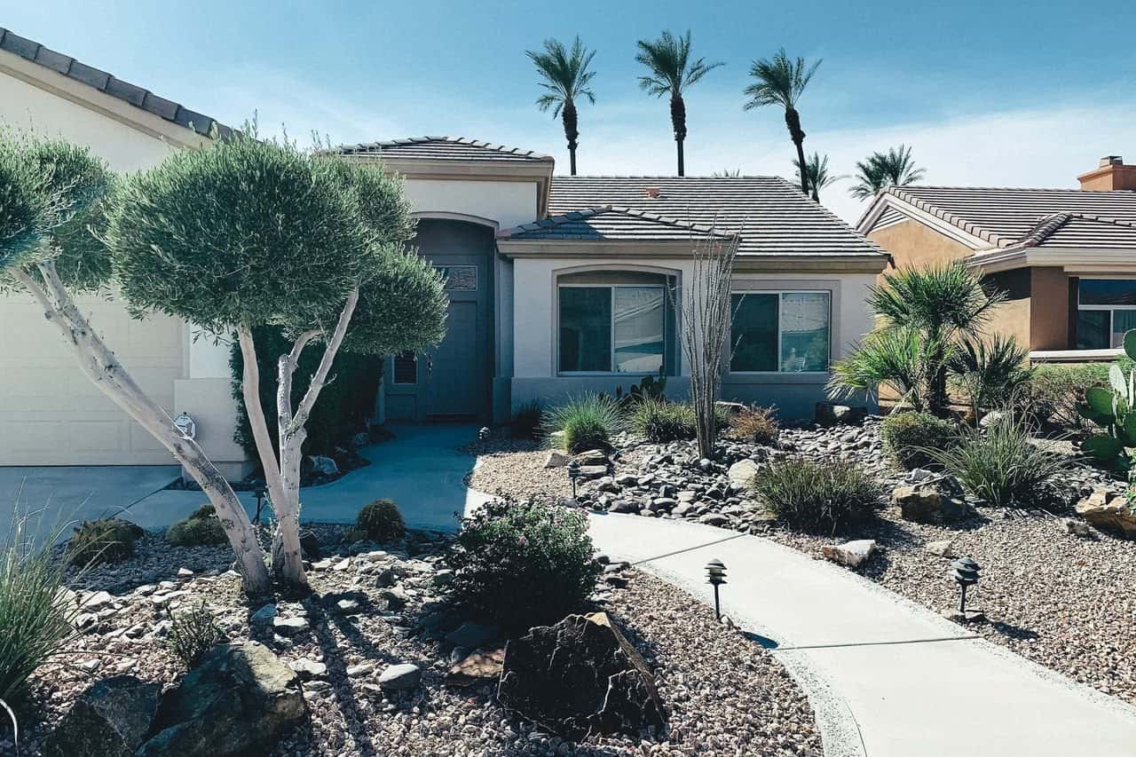 A single-family stucco home with desert landscaping and palm trees.